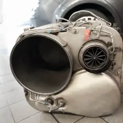 Element układu wydechowego, prawdopodobnie po usuwaniu filtra DPF. Widać dużą rurę i turbinkę.